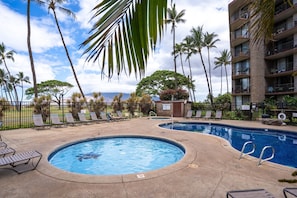 Relax by the circular pool surrounded by lounge chairs and umbrellas, with a scenic view of the surrounding landscape.