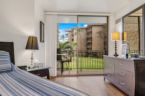 Relax in a spacious room with a large bed, bedside table, and sliding glass door leading to an outdoor area with a view.