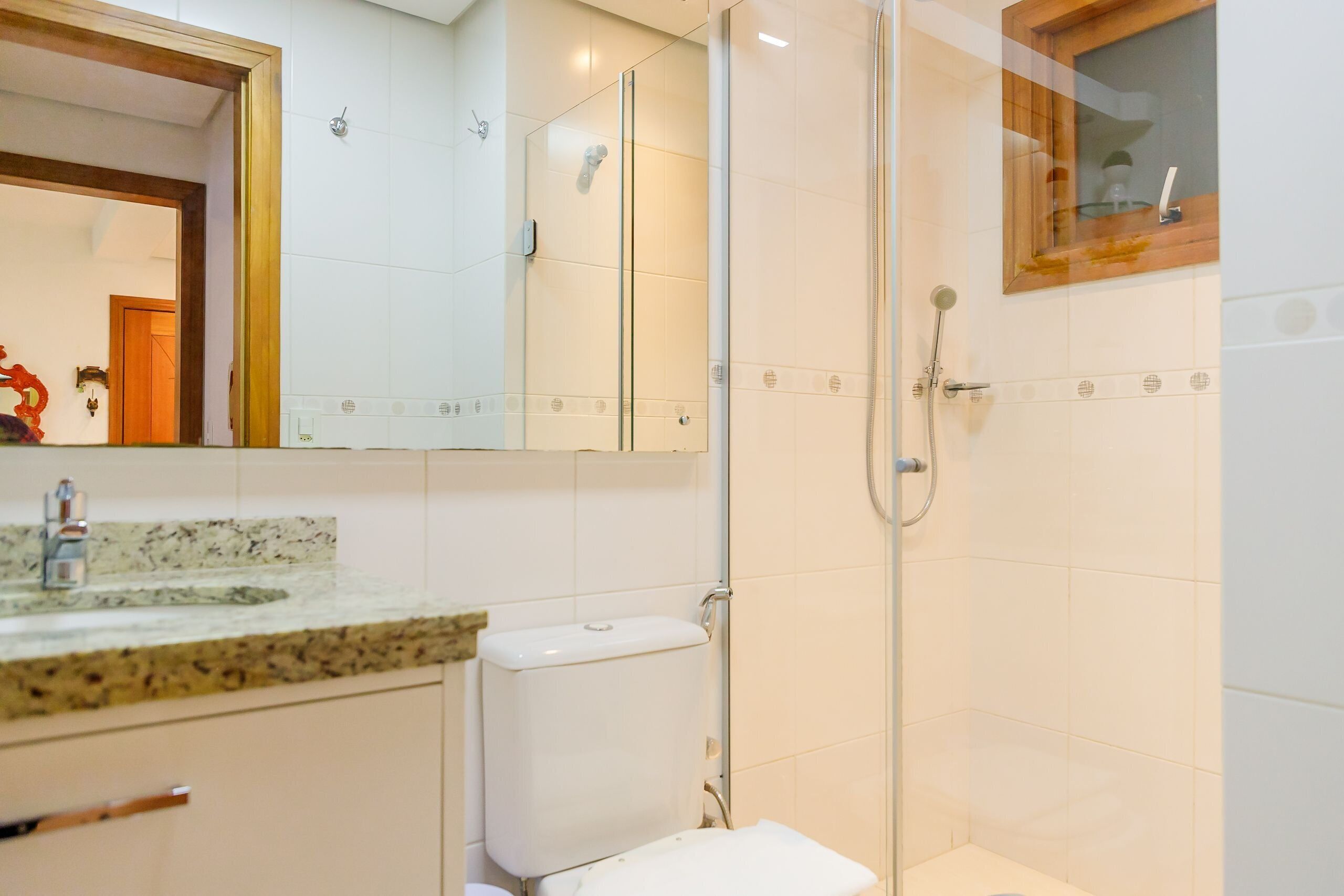 A bathroom with a glass-enclosed shower, a toilet, and a sink with a granite countertop.