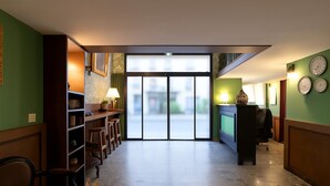 Vestíbulo de hotel con recepción, zona de estar y vistas a través de puertas de cristal.