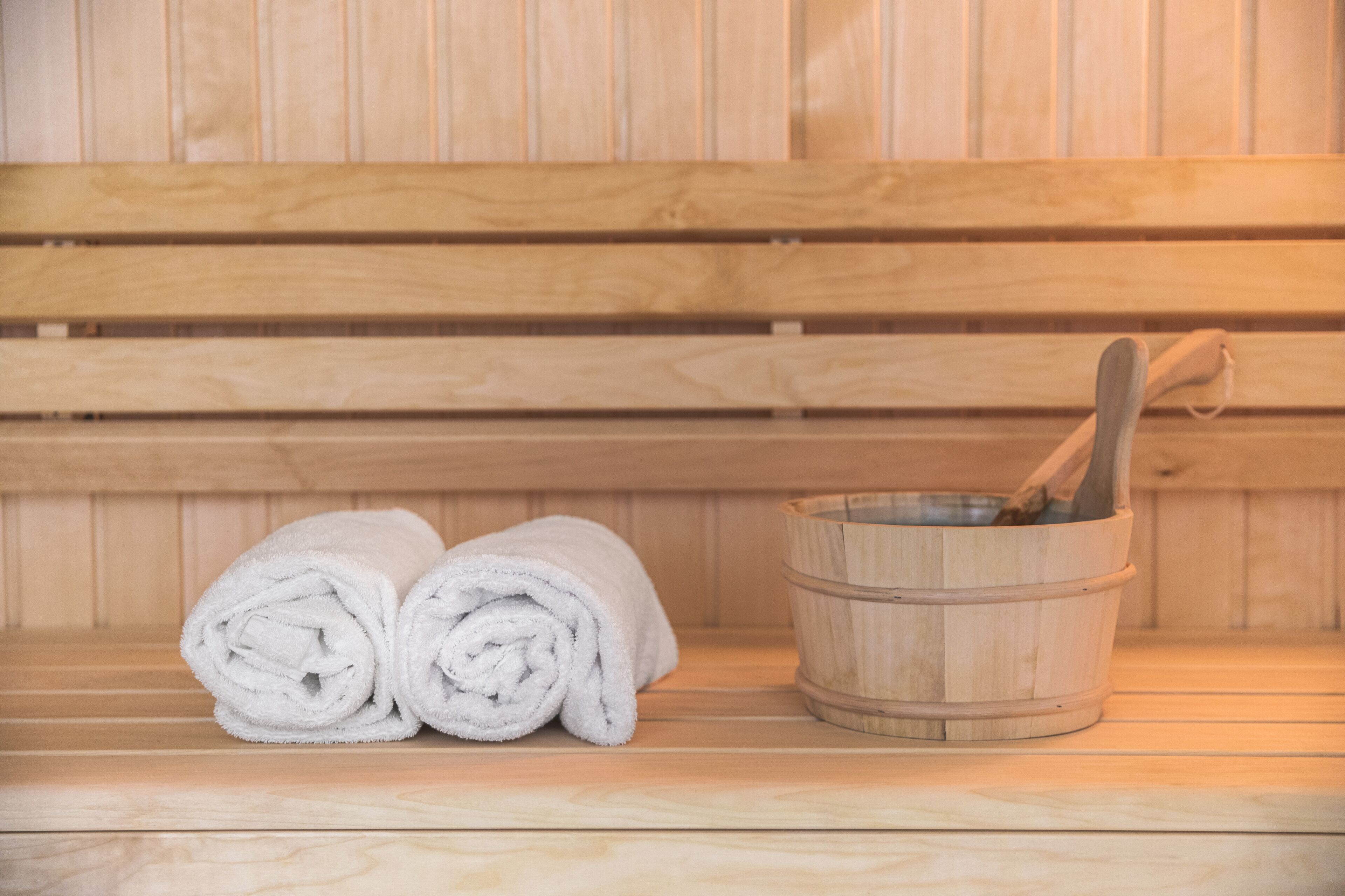 Eine Holzsauna mit einem Holzeimer und aufgerollten Handtüchern.