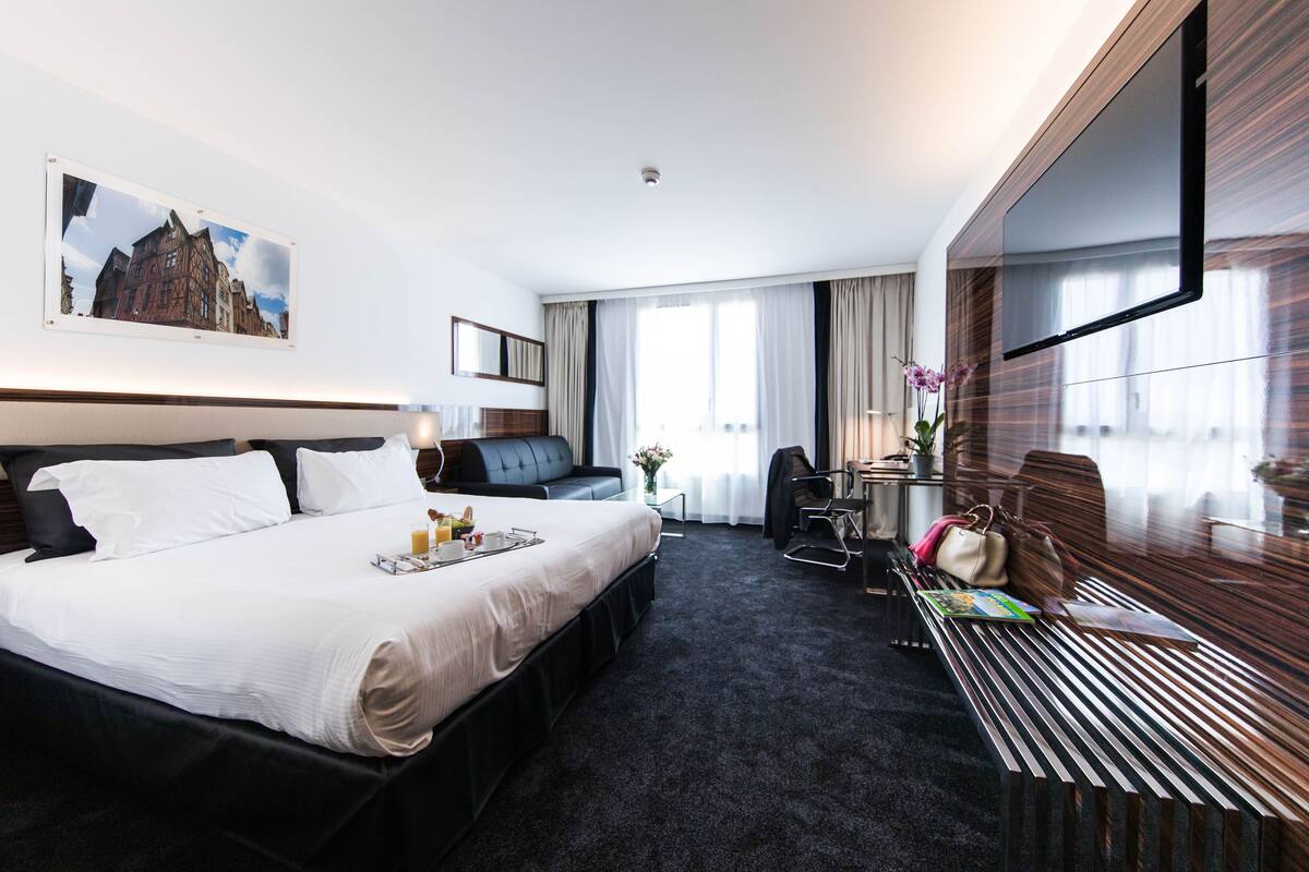 Ein modernes Hotelzimmer mit einem großen Bett, einem Schreibtisch und einem Fernseher.