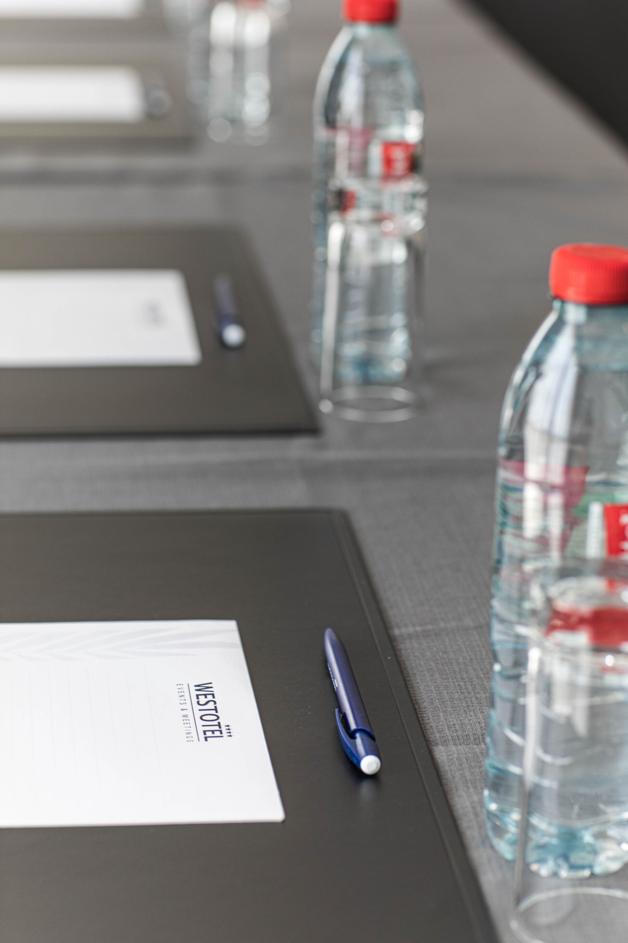 Une table de conférence avec des bouteilles d’eau, un stylo et une plaque nominative.