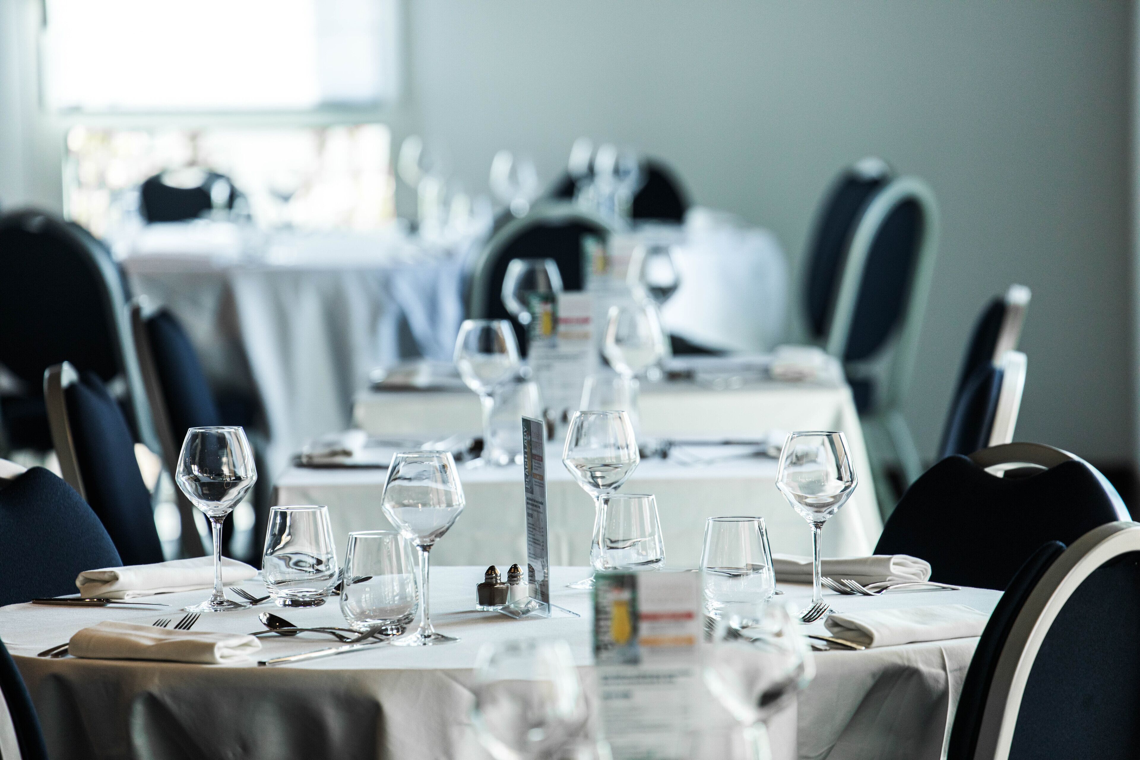 A restaurant with tables set for dining, featuring clear glassware and neatly arranged cutlery.