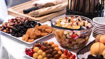 Una mesa de buffet con diversos alimentos, entre ellos frutas, frutos secos y pasteles.
