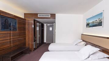 A hotel room with two beds, a TV, a wooden panel wall, and a framed picture on the wall.