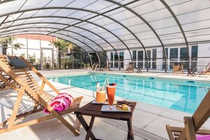 Una piscina techada, una piscina al aire libre de temporada, sombrillas