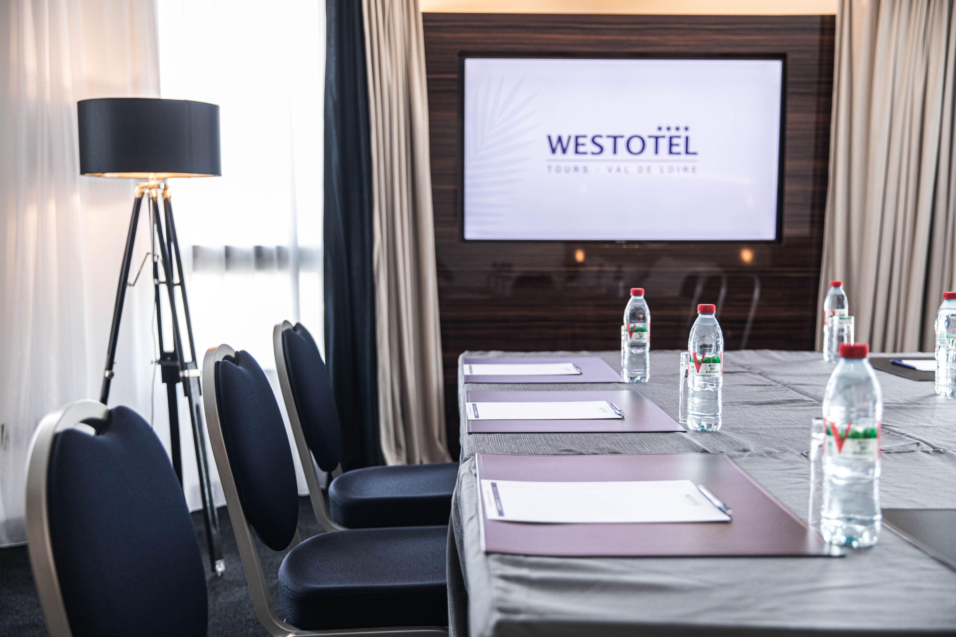 Un salón de conferencias con una pantalla grande mostrando 