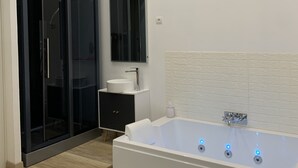 Um banheiro moderno com uma banheira grande, box de vidro e pia branca.