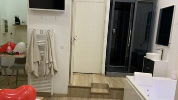 A modern hotel room with a flat-screen TV, a bathroom with a bathtub, and a staircase leading to another room.