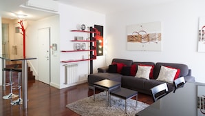 A modern living room with a grey sofa, a coffee table, and a red shelf unit.