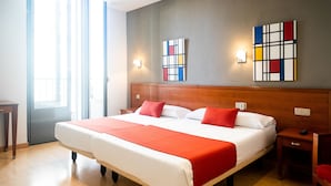 A hotel room with a large bed, wooden headboard, two bedside tables, a nightstand, and a red chair. - Hostal Persal (Madrid)