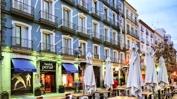 A hotel with outdoor seating, multiple balconies, and a storefront with a sign. - Hostal Persal (Madrid)