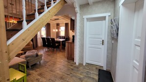 A spacious room with a wooden staircase, a dining area with a table and chairs, and a white door with a magazine rack. - Cottages Oberdorla at the center here in Germany Thüringen (Oberdorla)