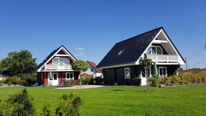 Two houses with sloped roofs and front porches, surrounded by a well-maintained lawn and small trees. - Cottages Oberdorla at the center here in Germany Thüringen (Oberdorla)