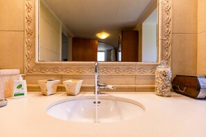 A bathroom with a large mirror, a sink, and toiletries.