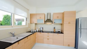 Una cocina moderna con armarios de madera clara, encimera negra, electrodomésticos de acero inoxidable y ventana que aporta luz natural.