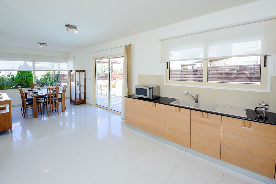 A modern kitchen with a black countertop, wooden cabinets, and a built-in microwave.