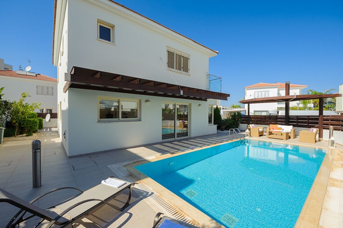 A modern two-story house with a swimming pool, outdoor seating, and a pergola.