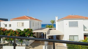 Una zona residencial costera con edificios blancos, tejados de tejas rojas y una vista despejada del mar.