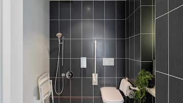 A modern bathroom with a shower, toilet, and a potted plant.