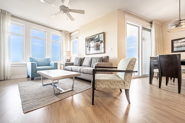 A spacious living room with a sofa, armchair, coffee table, and dining area.