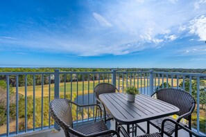 A balcony with a table and chairs overlooking a golf course.