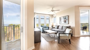Un salón amplio con balcón, ventilador de techo y un ventanal grande con vistas al exterior.