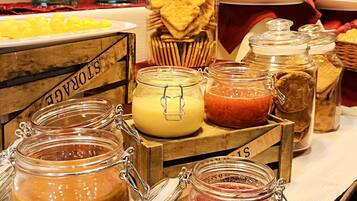 Un bufé con diversos alimentos, incluyendo frascos de crema de cacahuete, mermelada y una variedad de frutas.