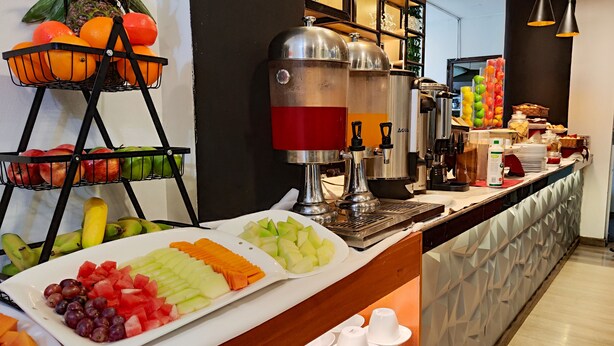 Zona de bufé con diversas frutas y una estación de café.