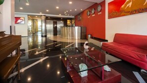 Un vestíbulo moderno con un sofá rojo, una mesa de centro de vidrio y un mostrador de recepción.