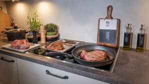 A kitchen with a stove, two pans, a cutting board, and various kitchen items.
