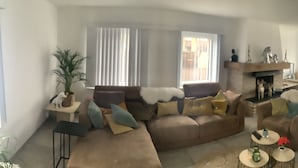 A living room with a sofa, coffee table, and a dining area with chairs and a table.