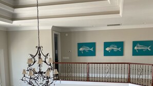 A spacious living area with a dining area, a chandelier, and artwork on the walls. - Luxury Waterfront Paradise at Ocean Isle Beach: Enjoy the Beach and Jink's Creek (Ocean Isle Beach)
