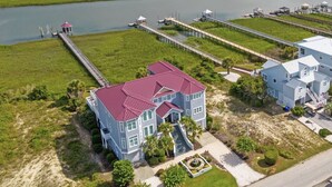A large house with a red roof, connected to a dock over water. - Luxury Waterfront Paradise at Ocean Isle Beach: Enjoy the Beach and Jink's Creek (Ocean Isle Beach)