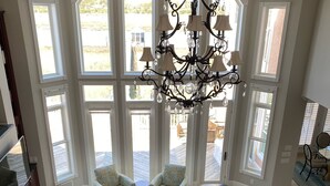 A spacious living room with a large sectional sofa, a wooden coffee table, and a chandelier. - Luxury Waterfront Paradise at Ocean Isle Beach: Enjoy the Beach and Jink's Creek (Ocean Isle Beach)