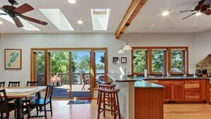A spacious kitchen with a central island, large windows, and a sliding glass door leading to an outdoor area. - Whitewater Lakefront Lodge with 200 Feet Shoreline Docks Sunset Views (Whitewater)