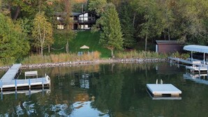 A lakeside property with a dock, a small boat, and a house surrounded by trees. - Whitewater Lakefront Lodge with 200 Feet Shoreline Docks Sunset Views (Whitewater)