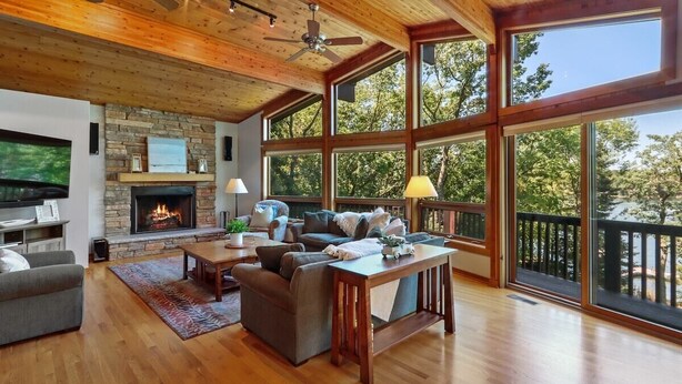 A spacious living room with a fireplace, large windows, and a wooden ceiling. - Whitewater Lakefront Lodge with 200 Feet Shoreline Docks Sunset Views (Whitewater)