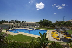Un espace piscine comprenant plusieurs piscines, des chaises longues et des parasols.