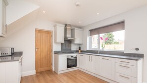 A modern kitchen with white cabinets, a built-in oven, and a window with a view of the outside. - 51 Main Avenue · Luxurious Modern York House with Garden & Parking - Pass the Keys (York)