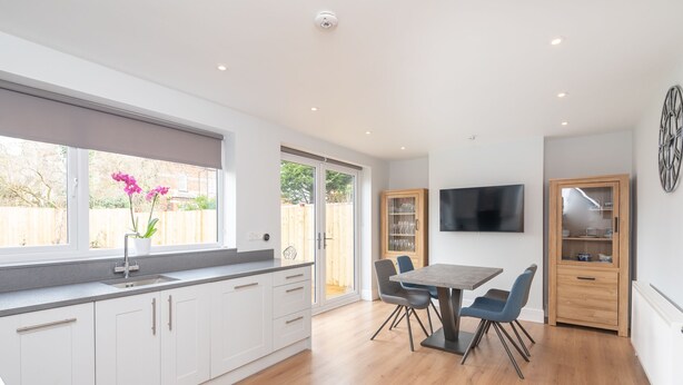 A modern kitchen with white cabinets, a large window, and a dining area with a table and chairs. - 51 Main Avenue · Luxurious Modern York House with Garden & Parking - Pass the Keys (York)