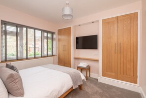 Quarto com cama, televisão na parede e guarda-roupa.