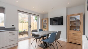 A modern kitchen with a dining table, chairs, and a built-in TV. - 51 Main Avenue · Luxurious Modern York House with Garden & Parking - Pass the Keys (York)