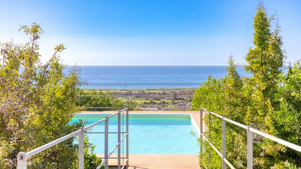 A pool with a view of the ocean, surrounded by greenery. - Superb villa with pool and 180° sea view (Torre Pali)
