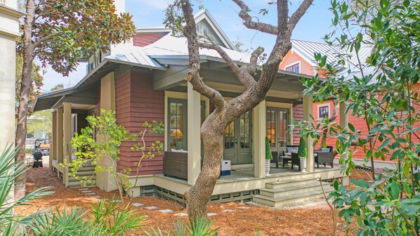 A house with a covered porch, a brick exterior, and a large tree in front. - WaterColor "Wine Down" | Sleeps 6 | 6 Seater Golf Cart |Walk to Beach | Bikes (Santa Rosa Beach)