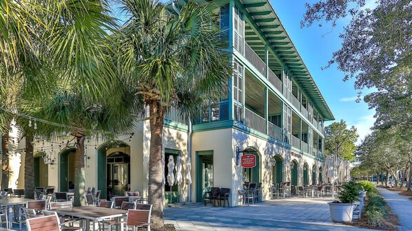 Un edificio histórico con mesas al aire libre y palmeras.