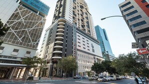 A modern high-rise building with a prominent glass facade, a unique geometric design on one side, and a series of balconies on the other. - 22nd Floor Apartment  With Mountain Views (Cape Town)
