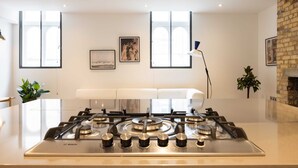 Une cuisine moderne dotée d’une cuisinière à gaz Bosch, de meubles blancs et de grandes fenêtres.