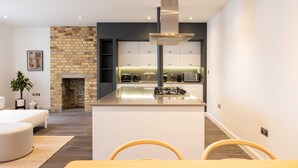 Une cuisine moderne dotée d’un îlot central, d’appareils électroménagers intégrés et d’une cheminée en pierre.